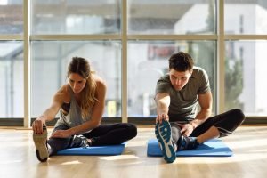 Paar mach Dehnübungen im Fitness-Studio